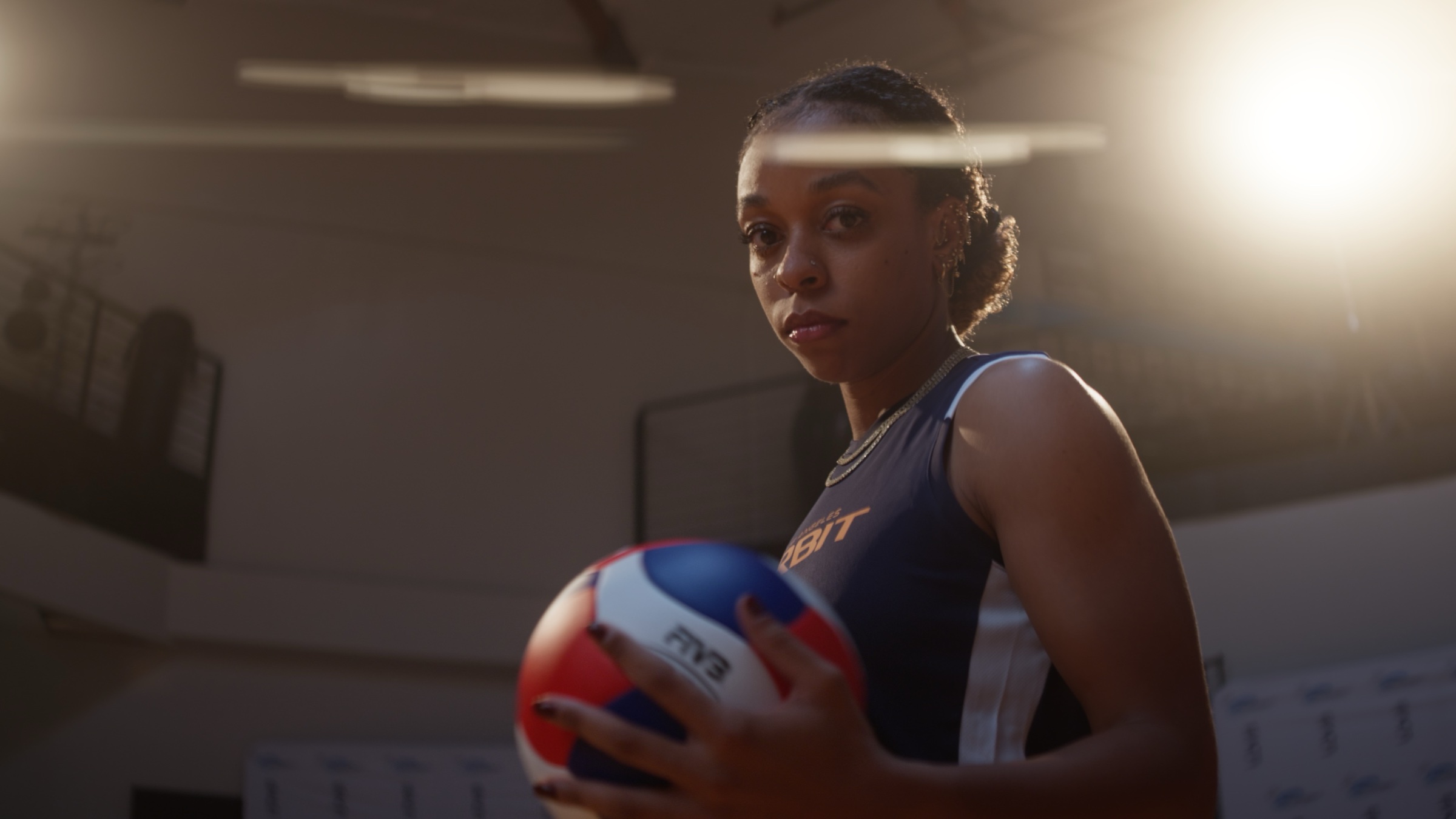 LA Orbit athlete holding a volleyball under warm gym lights